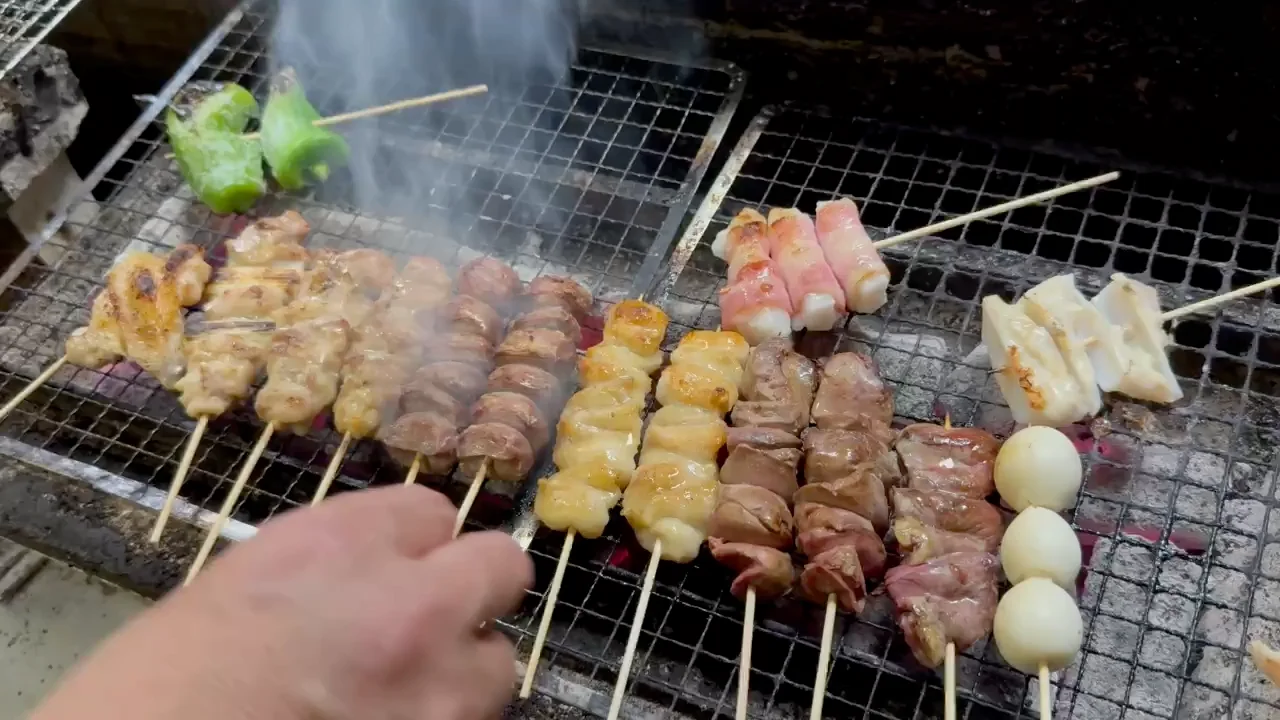煙が立ちのぼる炭火の上で、一本ずつ焼き上げる三文銭の串焼き
