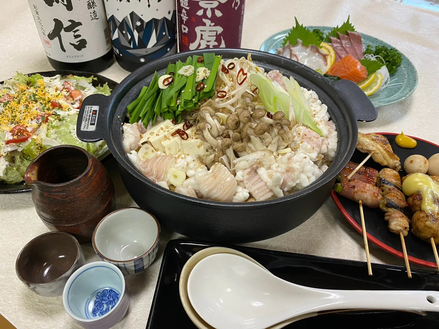 日本酒と三文銭の料理が並ぶ食卓